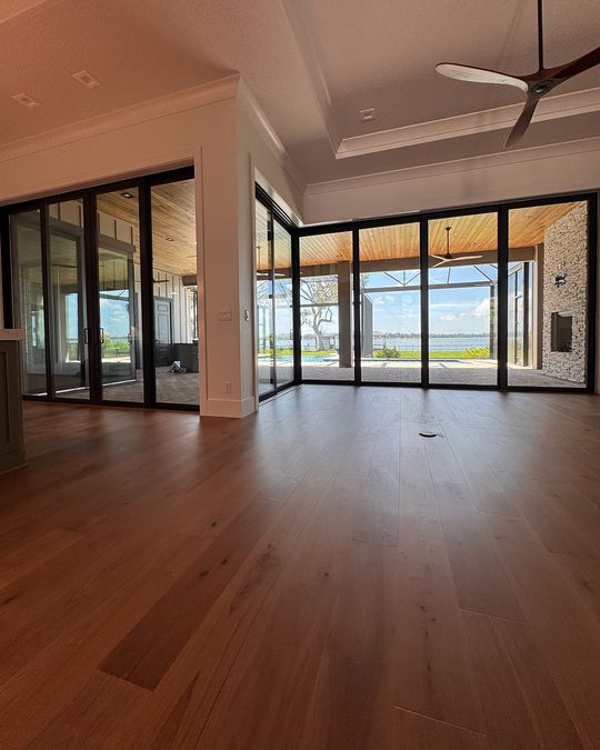 A great room with a wall of glass to the lanai and a hardwood floor in front.