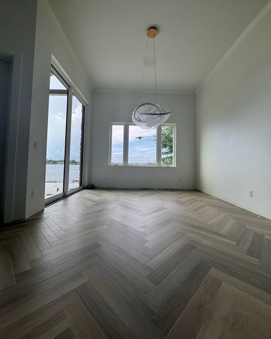A dining room with a sculptural light and a herringbone floor.