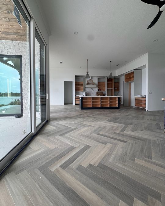 A gray herringbone floor running along a wall of glass to the far end of the room.