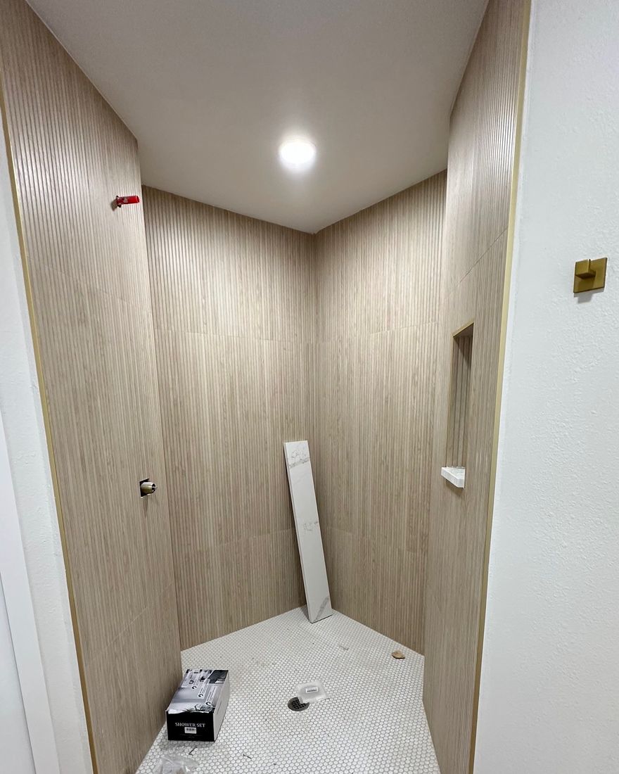 A shower with wood-look tile walls and a built-in niche.