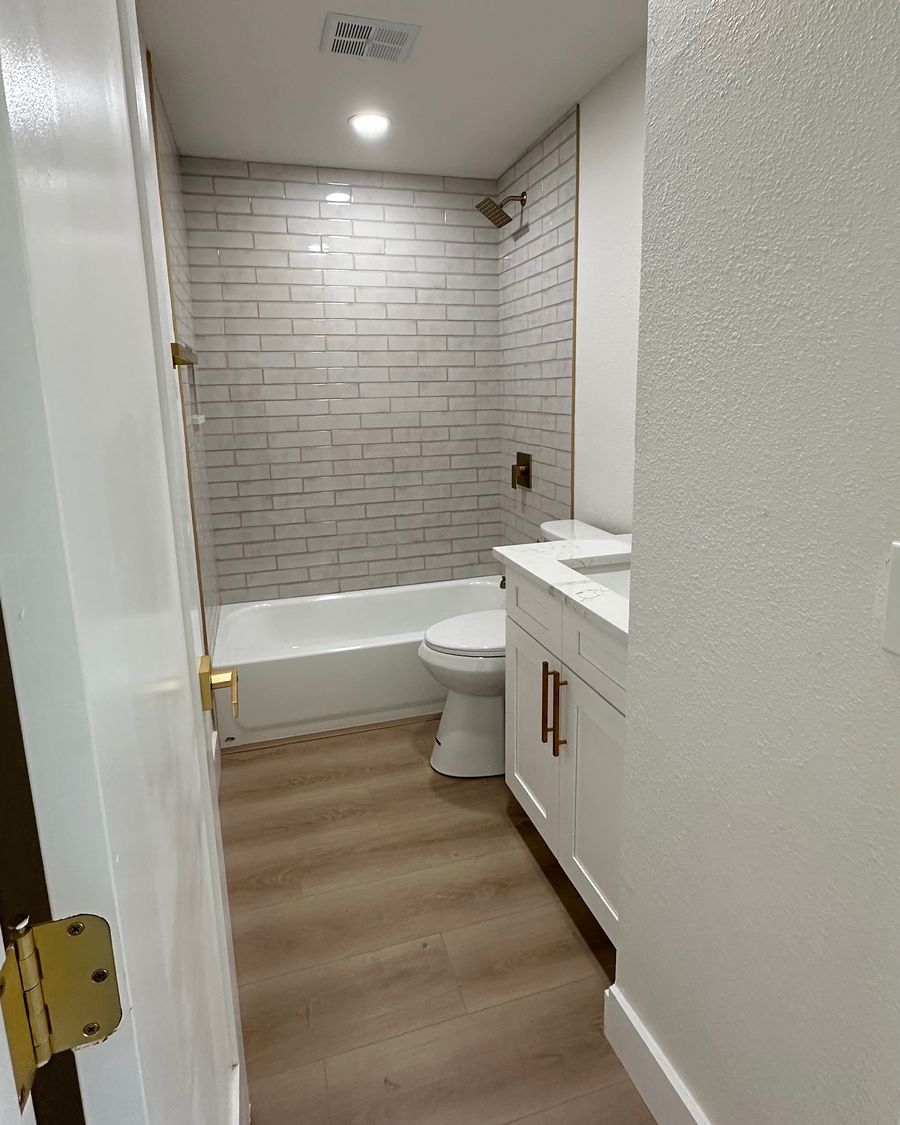 The same bathroom when done: a subway tile tub surround, a vanity and a new floor.