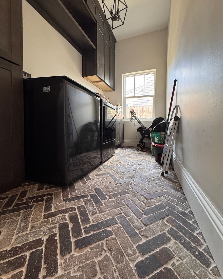 A laundry room with a brick herringbone floor in the foreground.