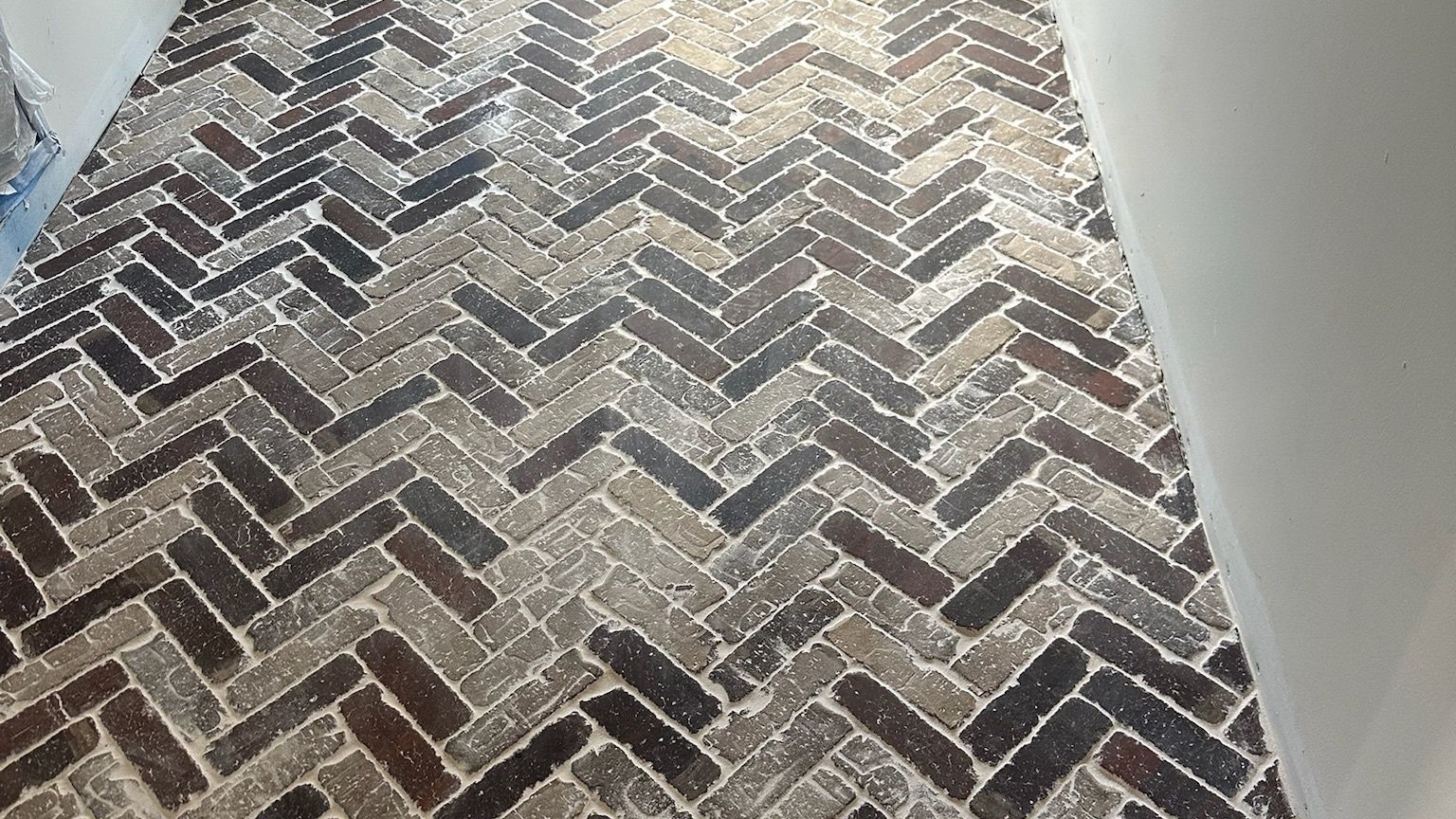 A rustic brick floor laid in a herringbone pattern.