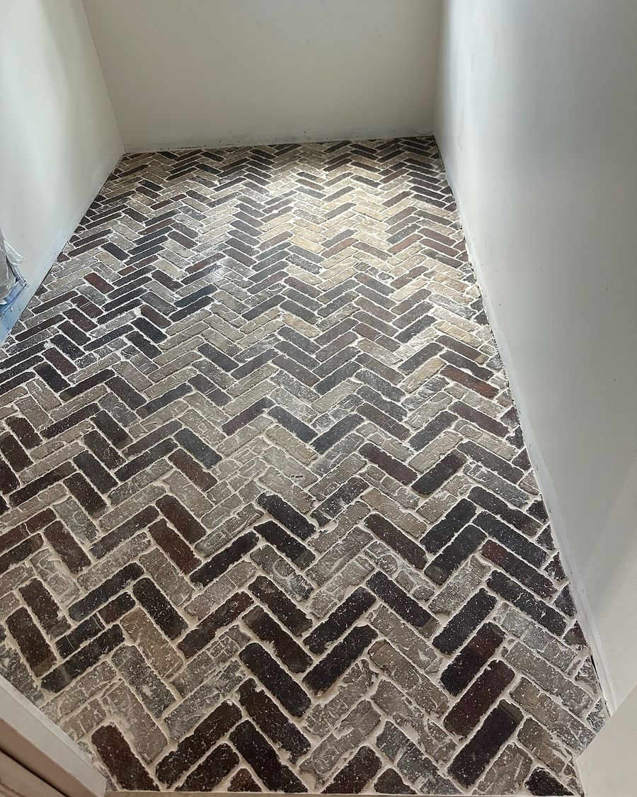 The same room when done: a rustic brick floor in a herringbone pattern.