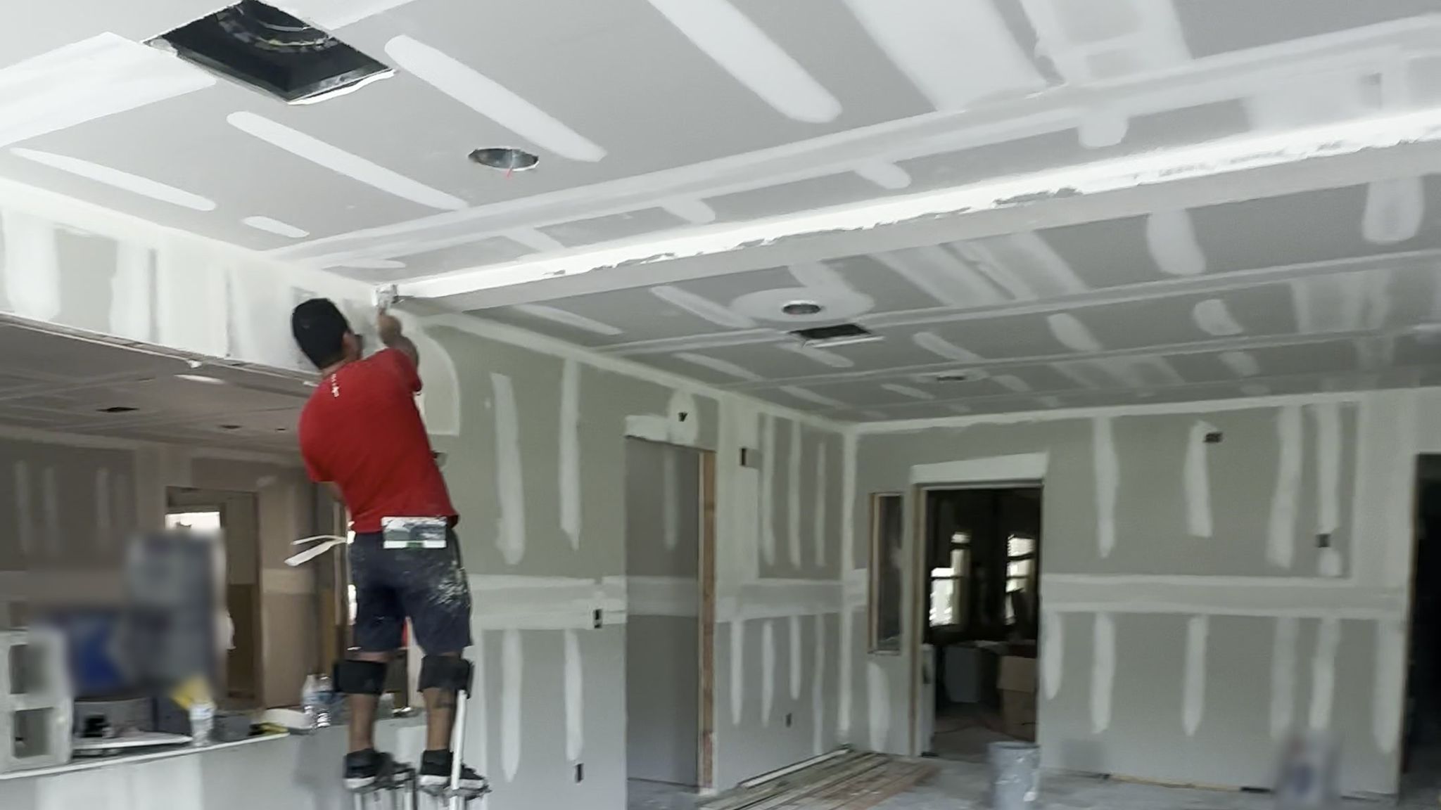 A drywall ceiling being finished with joint compound.