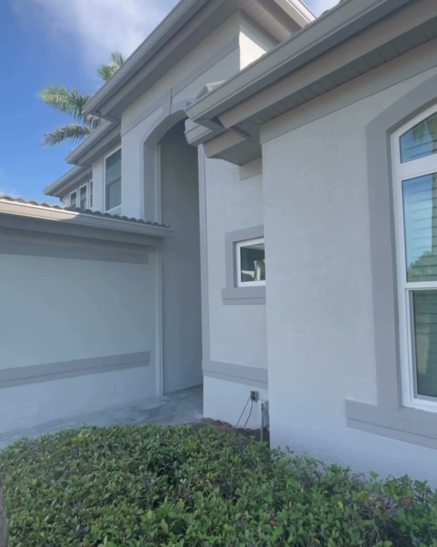 A freshly painted stucco wall with a raised trim band and an arched window.