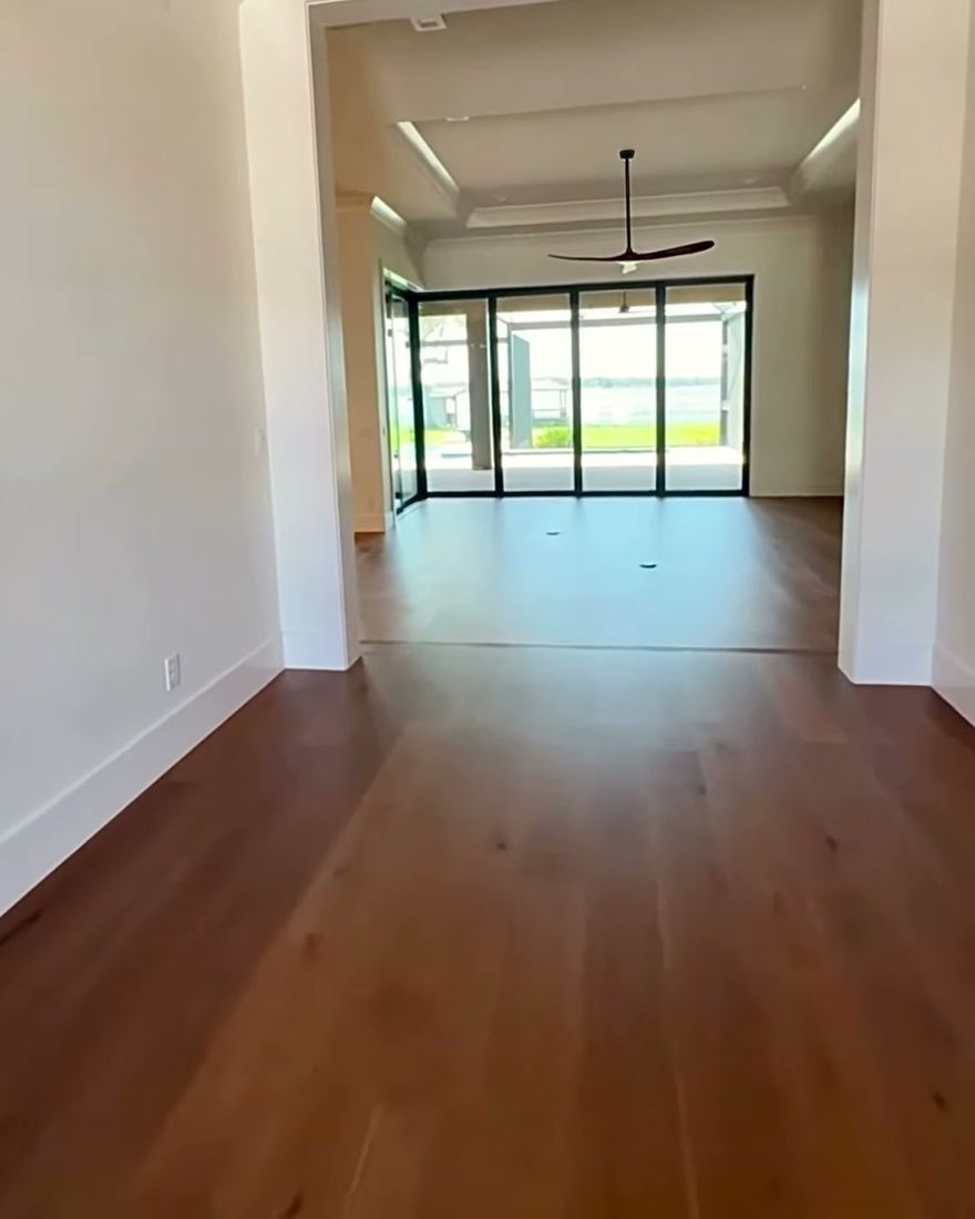 An arched hallway with a hardwood floor running into a bright room.