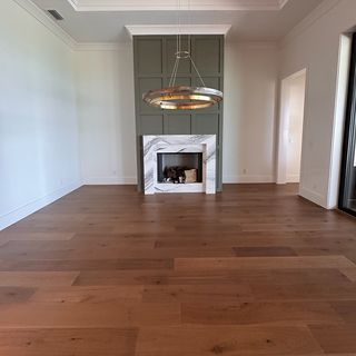 A living room with a wide-plank hardwood floor in front of the fireplace.