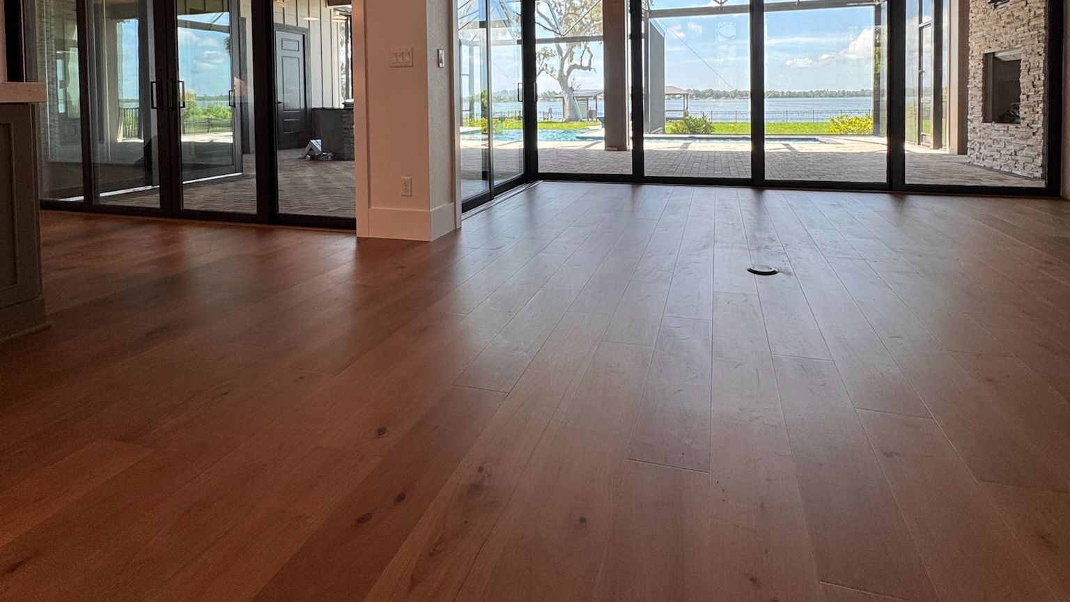 A great room with a wall of glass to the lanai and a wide-plank hardwood floor.