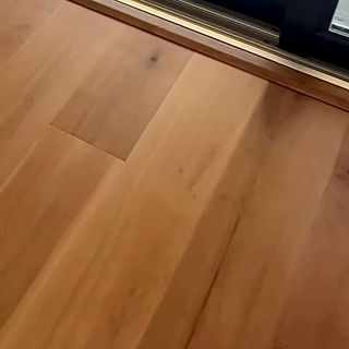 A hardwood floor cut clean along a glass slider track.