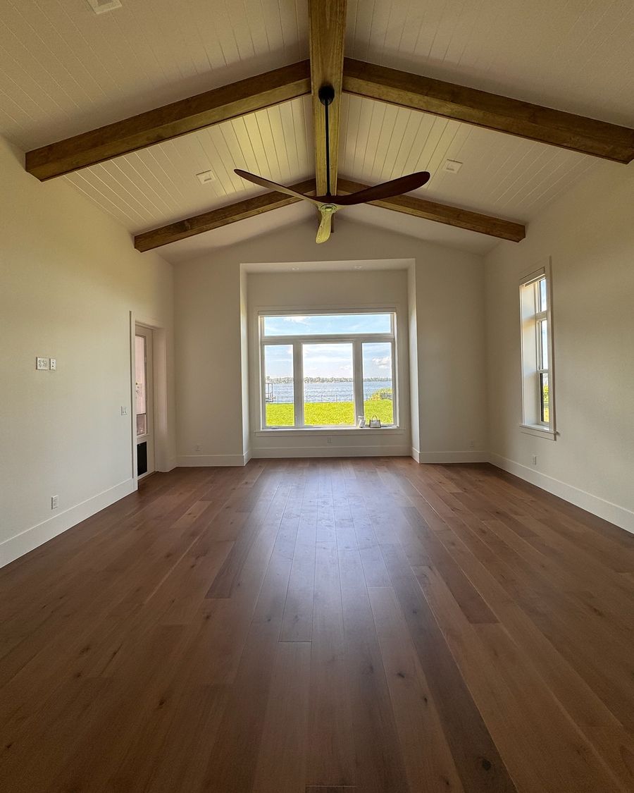 The same bedroom when done, with a wide-plank hardwood floor running to the window.