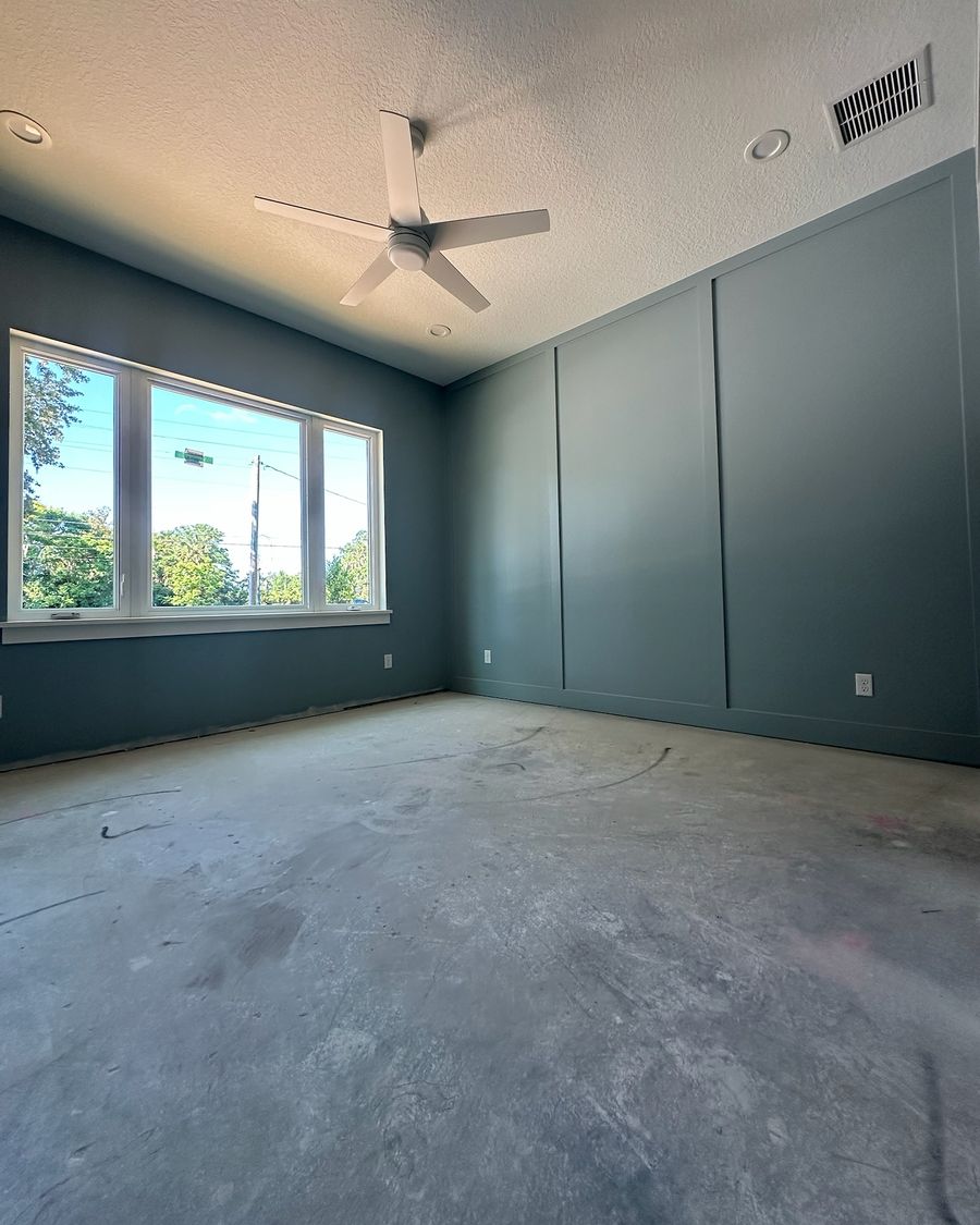 A bedroom with dark paneled walls on day one: a bare, marked concrete slab.