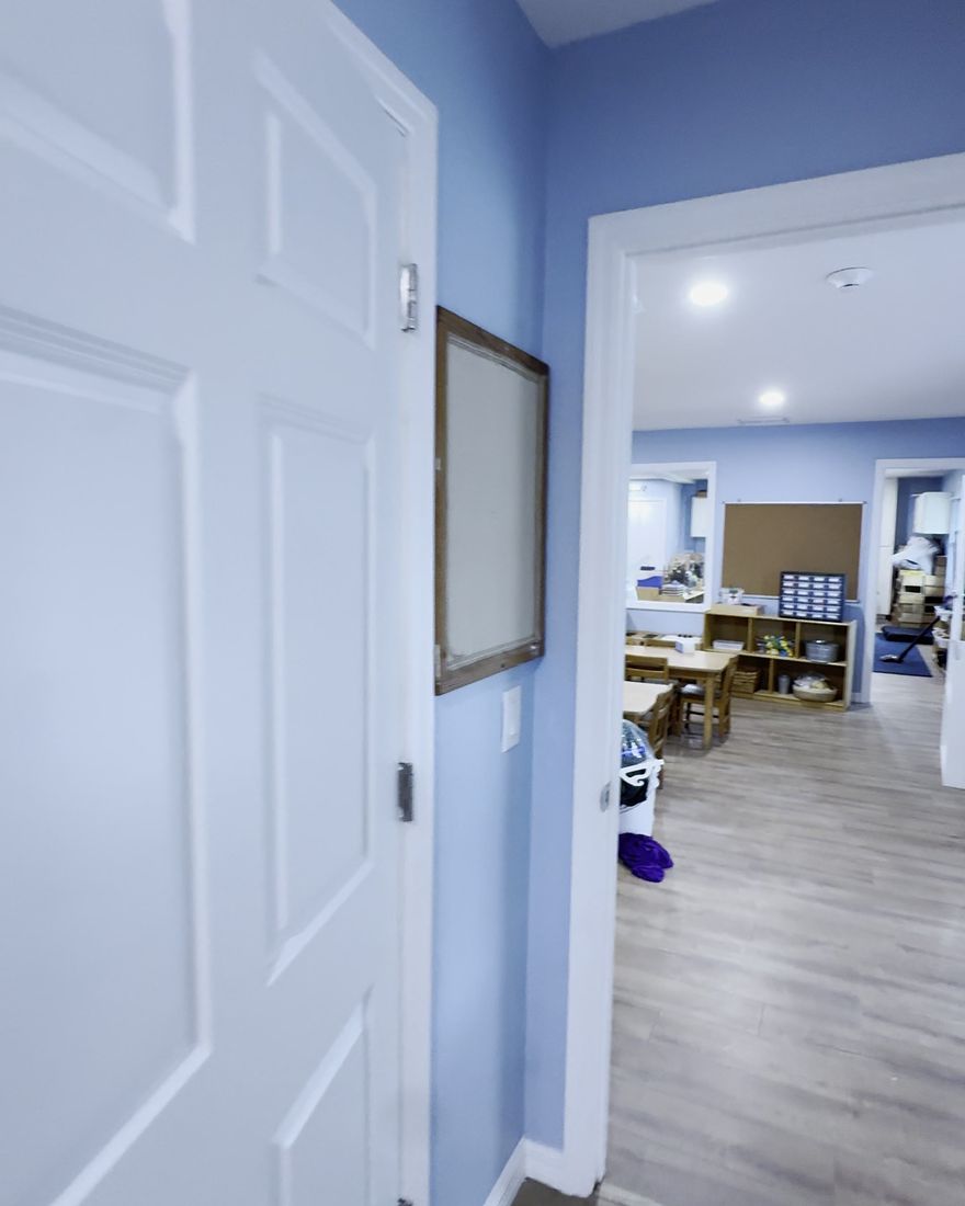 A six-panel white interior door with new casing and a new plank floor.