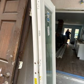 An old wood interior door next to its new white replacement with a glass panel.