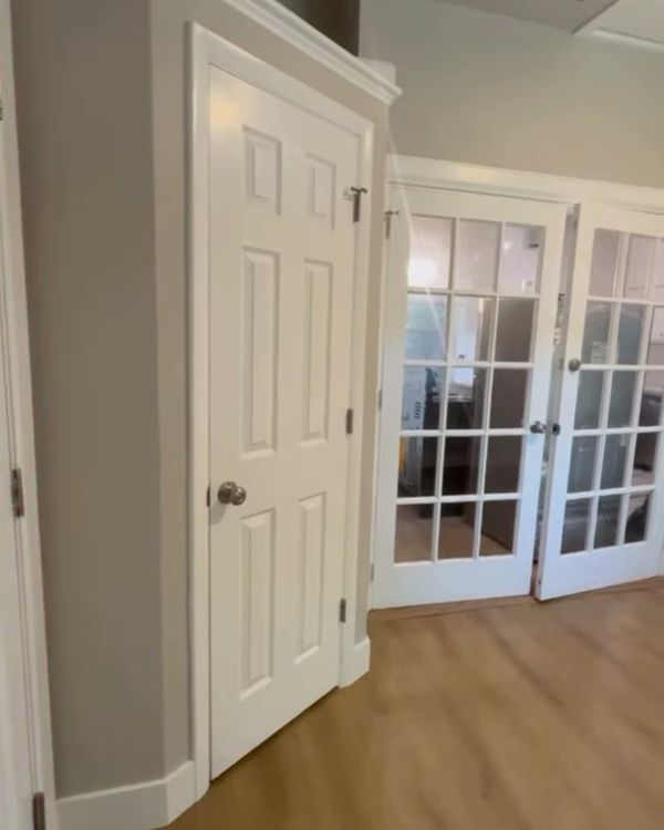 A six-panel interior door and a pair of glass-paneled interior doors with new baseboards.