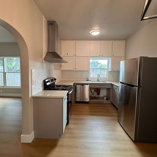 A finished kitchen seen through an arch, with a new plank floor in front.