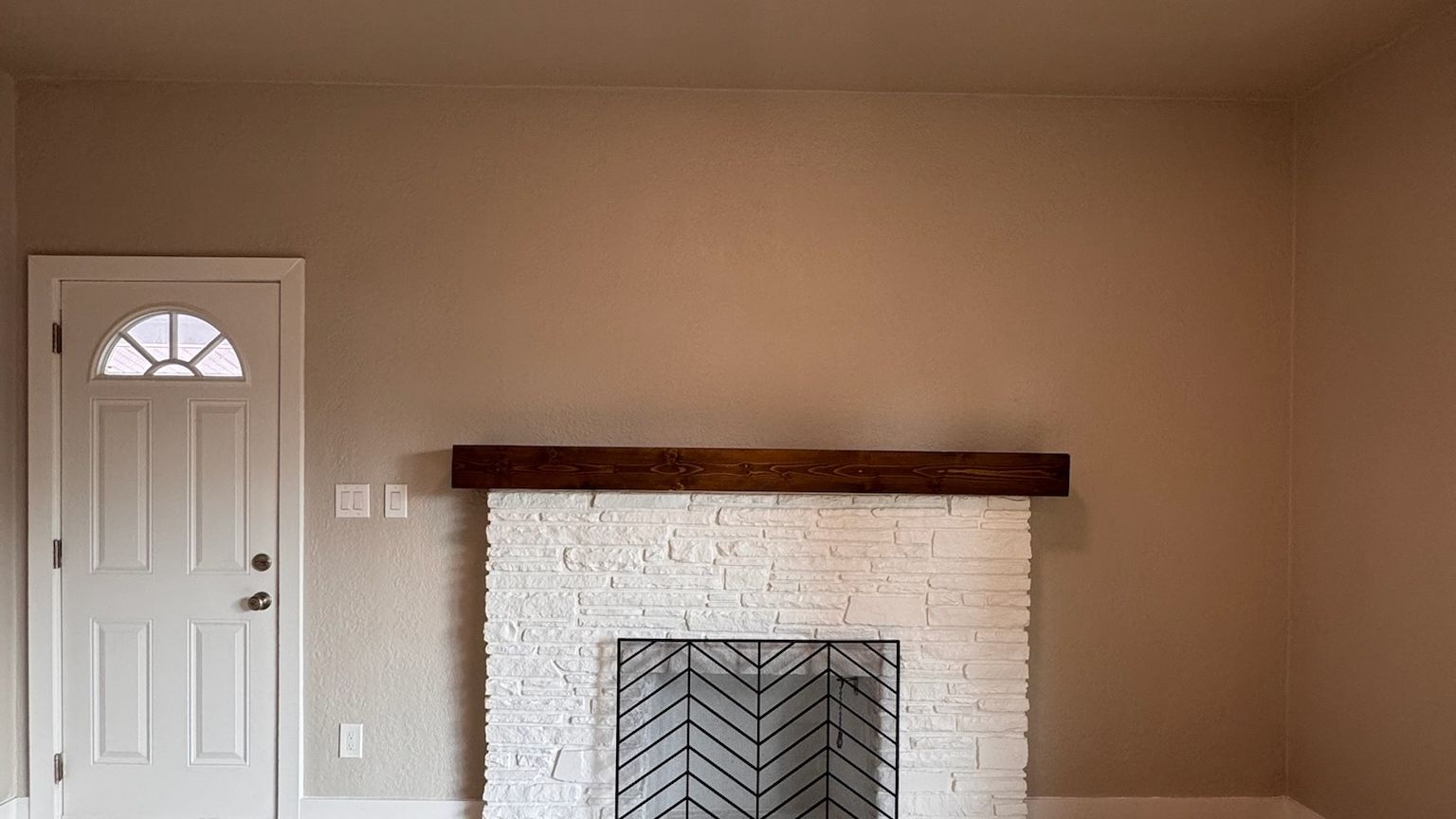 A freshly painted living room with a white brick fireplace.