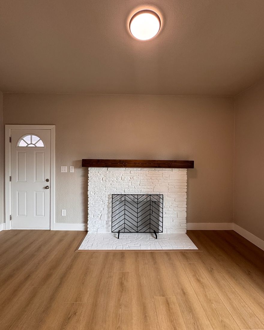 A living room with smooth painted walls and a white brick fireplace.