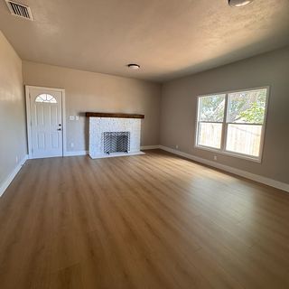 A living room with a white brick fireplace and a new plank floor.