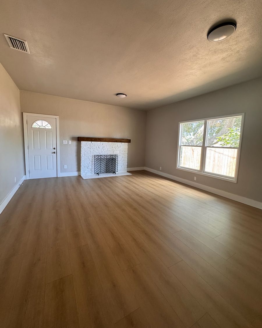 The same living room when done, with a white brick fireplace and a new plank floor.