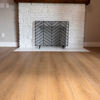A new wood-look plank floor meeting a white brick hearth, with a border piece around it.