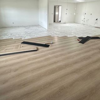 New wood-look planks going down over a thin underlayment sheet.