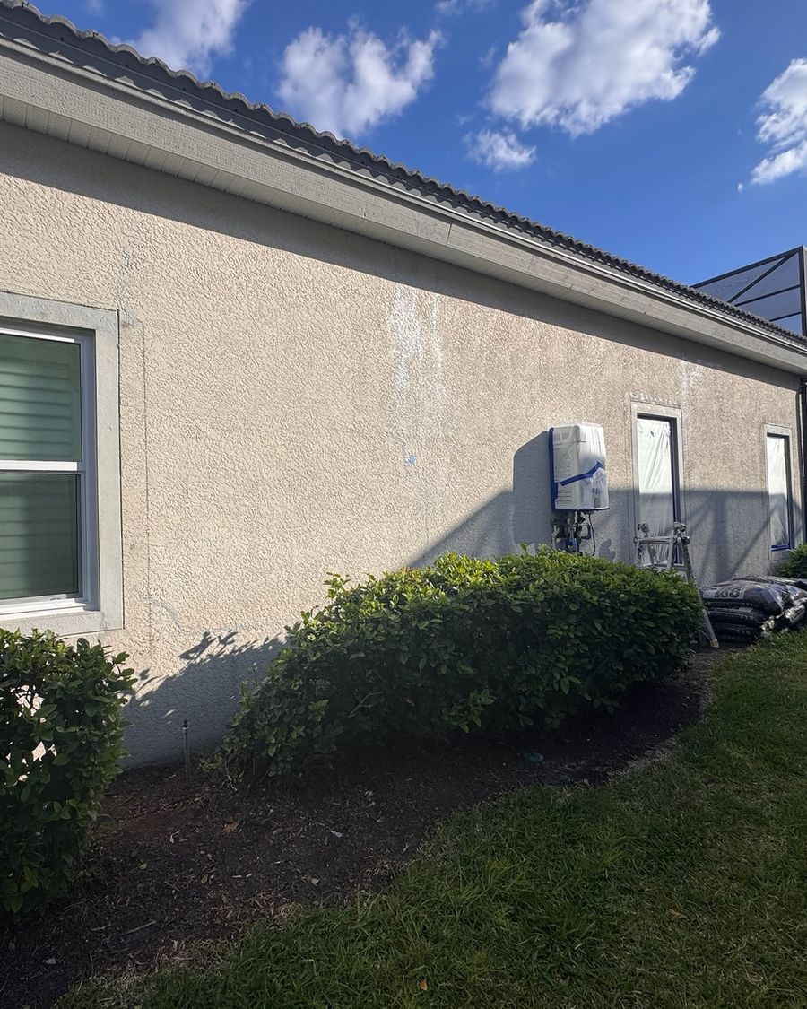 A stucco side wall before the repaint, with stains and patched spots.