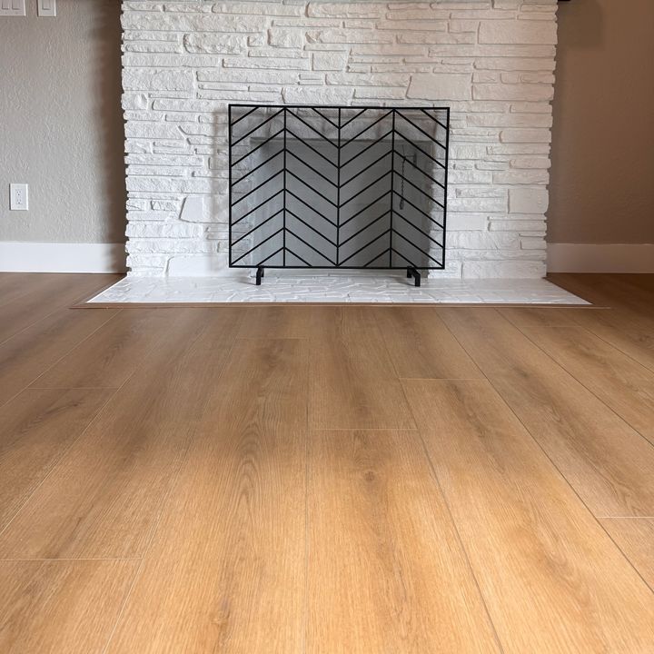 A new wood-look plank floor meeting a white brick hearth, with a border piece around the hearth.